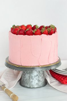 a strawberry cake with pink frosting and fresh strawberries on top, ready to be eaten