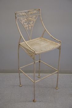 a white metal chair sitting on top of a tile floor next to a gray wall