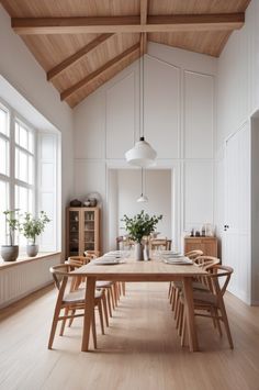 a dining room table and chairs in front of large windows with wooden beams on the ceiling