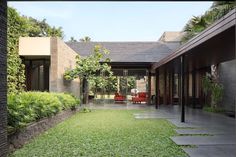 an outdoor area with grass and plants on the ground, in front of a house