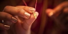 a woman holding a string with a small gold object on it