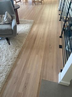 a living room with hard wood floors and white rugs on top of the floor