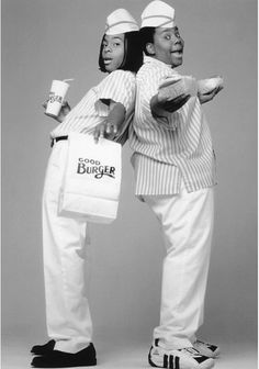 two black men dressed in white holding coffee cups and paper bags while standing next to each other