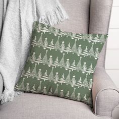 a green christmas pillow with white trees on it