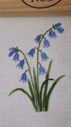 blue flowers are embroidered onto the back of a wooden frame