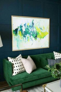 a living room with green couches and paintings on the wall