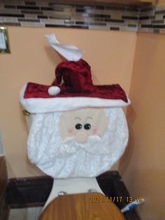 a toilet with a santa clause hat on it's back and seat cover over the top