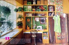 a yellow shelf filled with lots of green and white boxes next to a window covered in plants