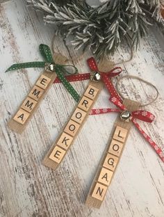 three wooden scrabble christmas ornaments on a table