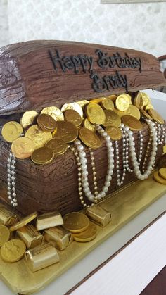 a birthday cake made to look like a boat with gold coins and pearls on it