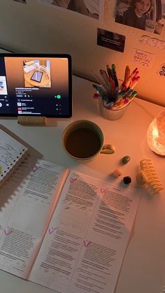 an open book sitting on top of a desk next to a cup of coffee and cell phone