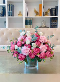 a vase filled with pink and white flowers sitting on top of a table next to a couch