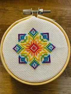 a colorful cross stitched design on a wooden surface