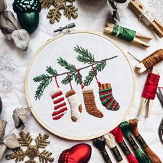 christmas stockings and socks are hanging on a tree branch in this hand embroidery pattern, surrounded by other holiday decorations