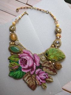 a close up of a necklace with flowers and leaves on it's chain,