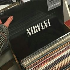 a person's hand pointing at the nirvana record album on display in a store