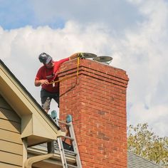 a man is working on the roof of a house with a chimney and ladders