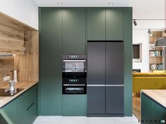 a modern kitchen with green cabinets and wood accents on the walls, along with a stainless steel refrigerator