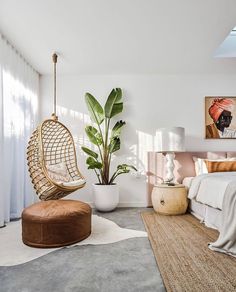 a bedroom with a bed, plant and hanging chair in the middle of the room