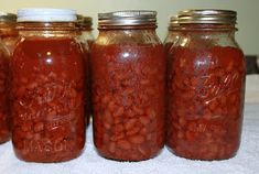 four jars filled with red beans sitting on top of a table