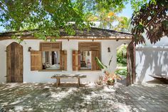 an exterior design on kolo with wooden shutters and wood doors, in front of a white house