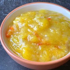 a bowl filled with soup sitting on top of a black counter next to a spoon