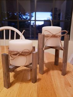 two white candles sitting on top of a wooden table