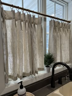 a bathroom with a sink, window curtain and faucet in front of it