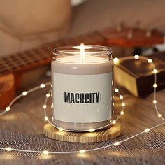 a candle sitting on top of a wooden table next to a guitar and string lights