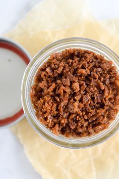 a glass jar filled with granola sitting on top of a white table next to an orange handled utensil