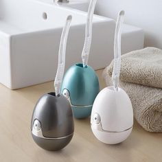 three different colored vases sitting next to each other on a wooden table with towels in the background