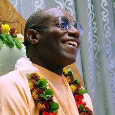 a man wearing sunglasses and leis smiles at the camera