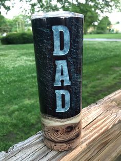 a cup that says dad on it sitting on top of a wooden post in the grass