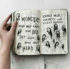 a hand holding an open book with writing on it and monsters drawn on the pages