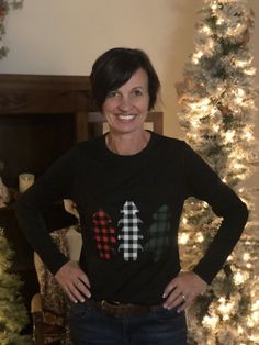 a woman standing in front of a christmas tree with her hands on her hips and smiling