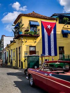 an old car parked in front of a building with a flag hanging from it's roof