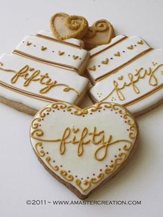 four decorated cookies in the shape of hearts with words on them that say happy 50th