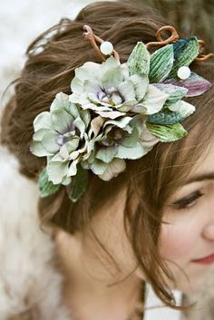 a close up of a woman wearing a flower headpiece with leaves and flowers on it