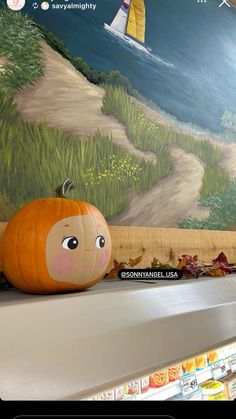 a pumpkin sitting on top of a shelf in front of a wall with a painting