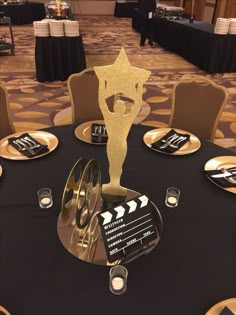 a black table topped with gold plates and an award trophy next to a movie clapper