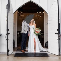 a bride and groom standing in the doorway of their barn