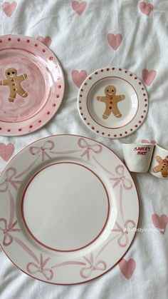 pink and white plates with gingerbread cookies on them are sitting on a tablecloth