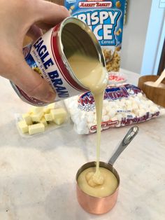 a person pouring caramel sauce on marshmallows in a small metal cup