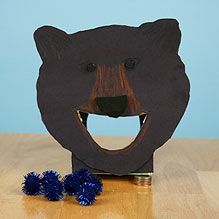 a wooden bear head with two blue pom - poms