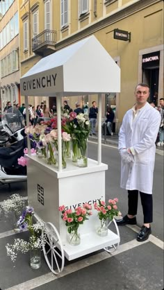 a man standing next to a white cart filled with flowers