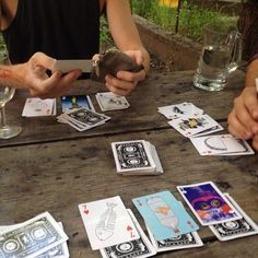 people playing cards at an outdoor table with wine glasses