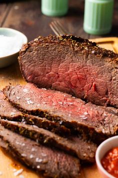 sliced steak on cutting board with sauce and fork