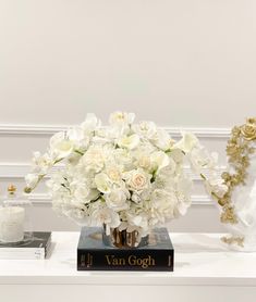 a bouquet of white flowers sitting on top of a book next to a candle holder