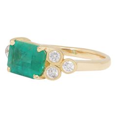 an emerald and diamond ring with three diamonds