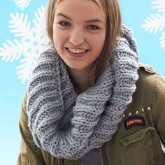 a woman wearing a gray knitted cowl with snowflakes in the background